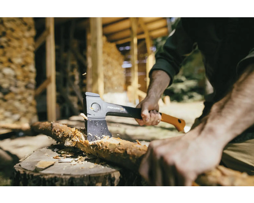 Mann spaltet Holz mit einer Fiskars Axt auf einem Baumstumpf.