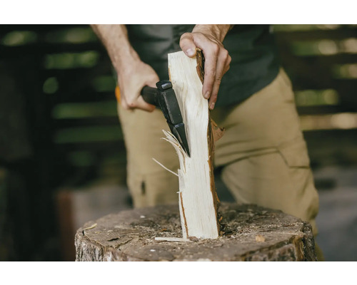 Mann spaltet Holz mit einer Spaltaxt auf einem Hackklotz