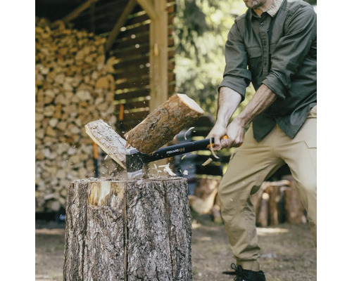 Homme fendant du bois avec une hache Fiskars sur un billot