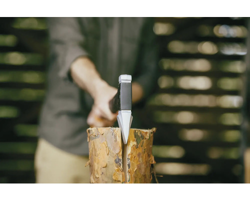 Un homme fend une bûche avec une hache à fendre.