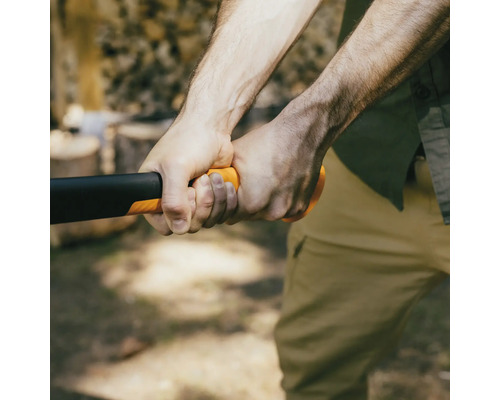 Gros plan d''une personne tenant une hache avec une tête noire et un manche orange
