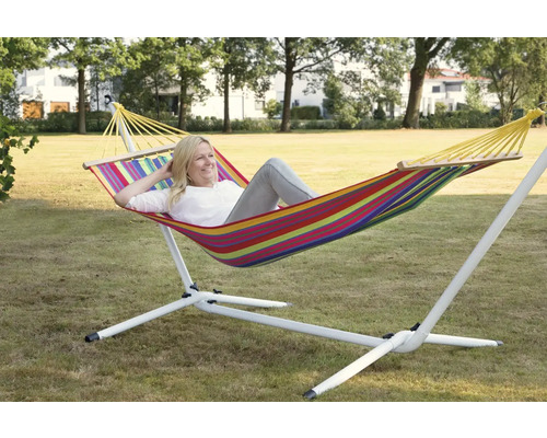 Femme se détend dans un hamac rayé avec support dans le jardin.