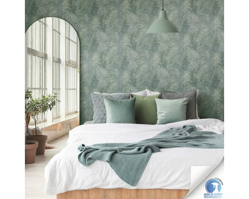 Schlafzimmer mit Bett vor einer mit Palmenmustern verzierten Wand