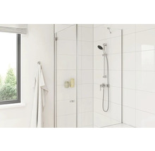 Cabine de douche avec parois en verre, serviette et robinetterie dans une salle de bain claire.