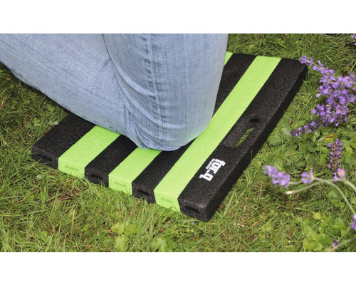 Personne agenouillée sur un tapis de jardin rayé sur une pelouse