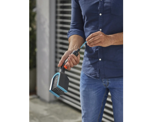 Une personne remplit une brosse avec un bâton de nettoyage pour l''irrigation du jardin.