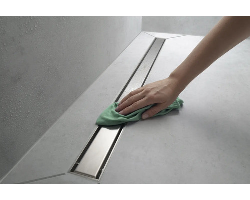 Une personne nettoie un caniveau de douche avec un chiffon