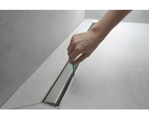 Nettoyage d''une rigole de douche avec un outil.