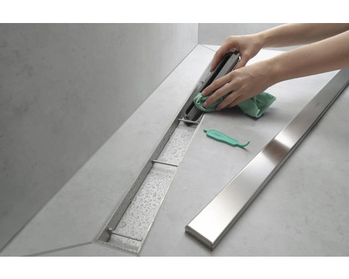 Nettoyage d''un caniveau de douche en acier inoxydable dans la salle de bains.