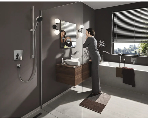 Salle de bains moderne avec douche, meuble sous-lavabo, baignoire et une femme devant le miroir