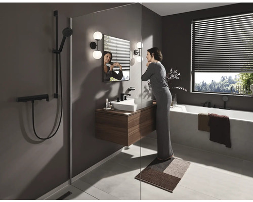 Salle de bains lumineuse avec douche, lavabo, miroir, baignoire et une femme