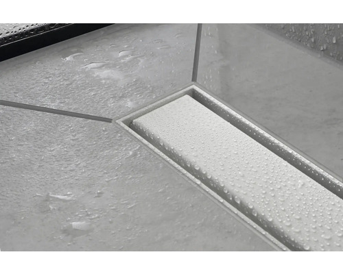 Edelstahl Duschrinne mit Wasserperlen auf Fliesenboden