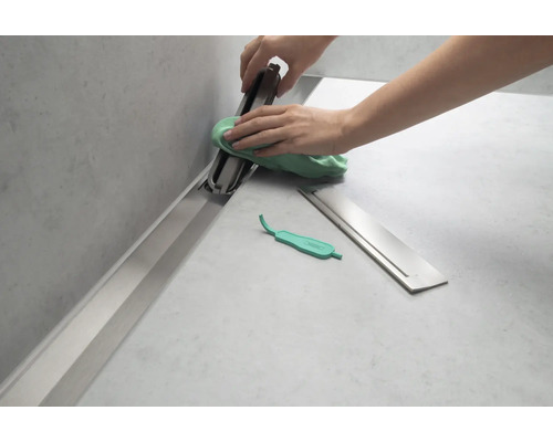 Reinigung einer Duschrinne mit einem Tuch und einem Werkzeug zum Anheben des Abflussrosts