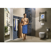 Badezimmer mit Dusche, Toilette und einem Mann mit Handtuch