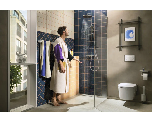 Salle de bains moderne avec douche, toilettes et lavabo, ainsi qu''un homme en peignoir vérifiant la température de l''eau de la douche.