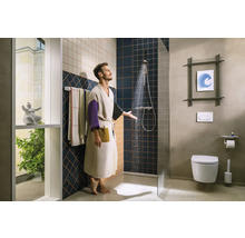 Mann unter der Dusche in einem Badezimmer mit Toilette und Handtüchern.