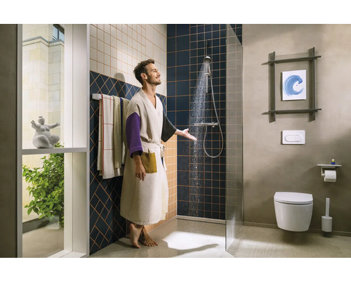 Homme sous la douche dans une salle de bains avec toilettes et serviettes.
