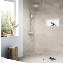 Begehbare Dusche mit Kopfbrause, Handbrause und Thermostatarmatur in einem Badezimmer mit Fliesen und Dekorationsartikeln