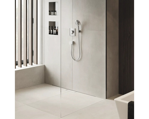 Begehbare Dusche mit Armatur, Brausekopf und Ablagefächern für Badprodukte.