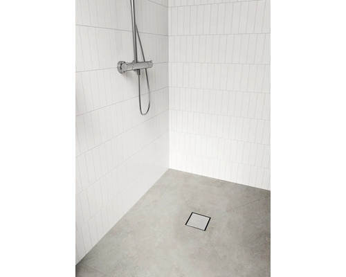Espace douche avec robinetterie, carreaux muraux blancs et drain de sol