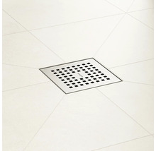 Évacuation de douche carrée en métal avec motif à fentes dans une zone de douche carrelée