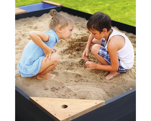 Zwei Kinder spielen in einem Sandkasten im Garten.