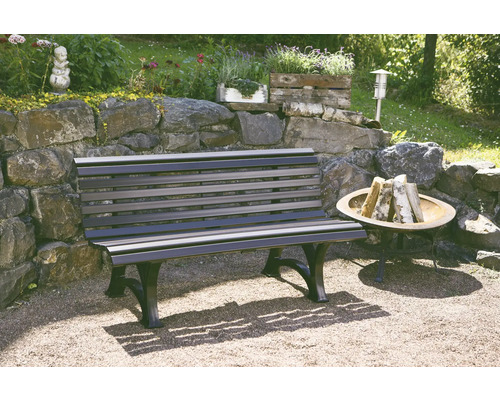 Un banc de jardin en bois et en métal se trouve dans le jardin à côté d''un foyer.