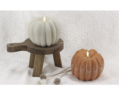 Dekorative Kürbiskerzen auf kleinem Holzschemel