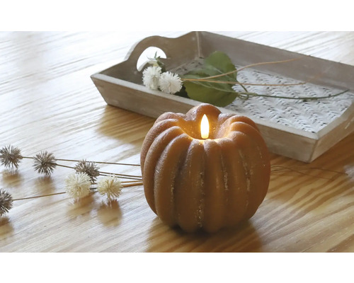 Dekorative Kürbiskerze mit LED-Licht auf einem Tisch mit Holztablett