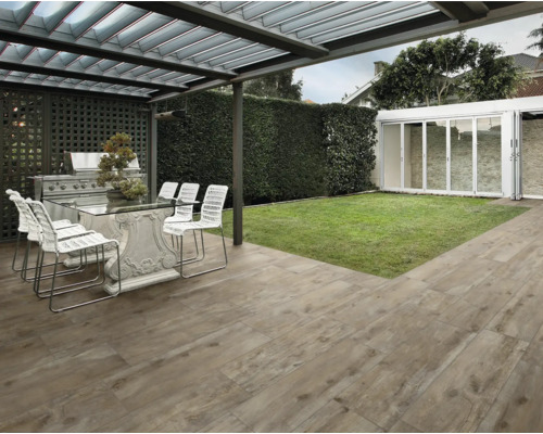 Terrasse mit Terrassenplatten in Holzoptik, Tisch, Stühlen und Grill unter einer Überdachung