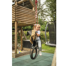 Fillette sur un cheval à bascule devant une cabane de jeu dans le jardin