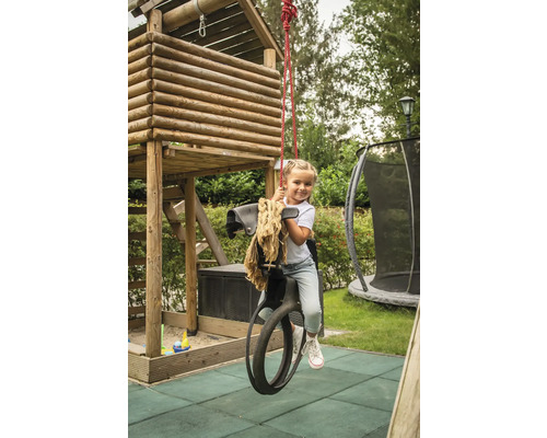 Fillette sur un cheval à bascule devant une cabane de jeu dans le jardin