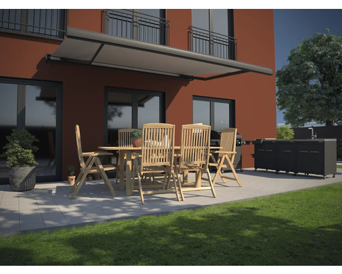 Terrasse avec store, table de jardin, chaises et cuisine de grill devant une maison