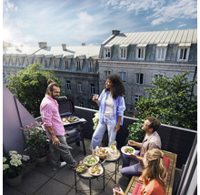 Groupe de personnes faisant des grillades sur un balcon avec barbecue, tables d''appoint, saladiers et sièges.