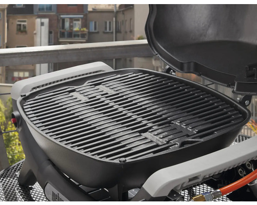 Barbecue à gaz Weber avec grille et couvercle ouvert.