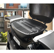 Barbecue Weber Q avec couvercle ouvert sur un balcon.