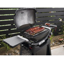 Barbecue Weber avec des côtes levées sur la grille dans le jardin.