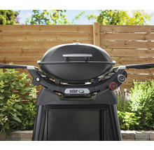 Barbecue à gaz Weber Q noir avec support devant une clôture en bois