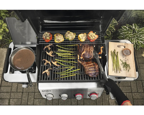 Gril à gaz avec des aliments grillés tels que steak, légumes et poivrons farcis.
