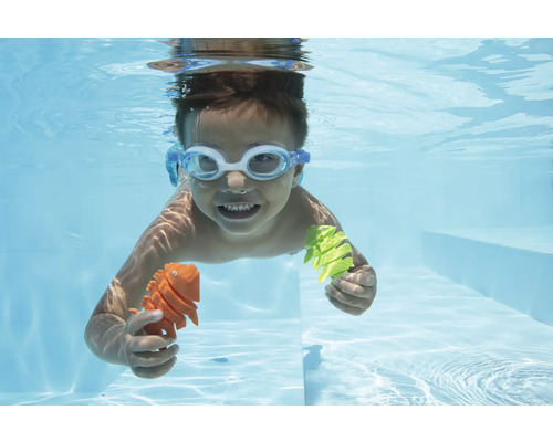 Kind mit Schwimmbrille taucht im Pool und hält Spielzeugfiguren in den Händen