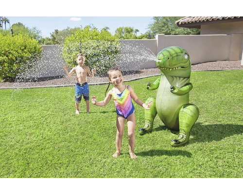 Arroseur dinosaure gonflable avec des enfants qui jouent dans le jardin.