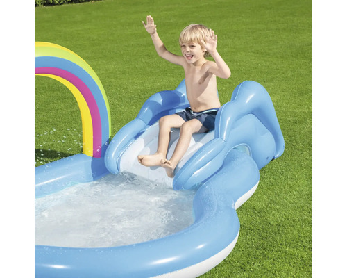 Junge rutscht auf einer aufblasbaren Wasserrutsche mit Regenbogen in einen Pool