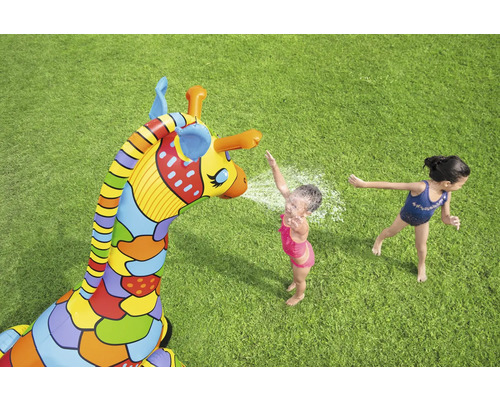 Aufblasbare Giraffe mit Wassersprinklerfunktion und spielenden Kindern auf einer Rasenfläche.