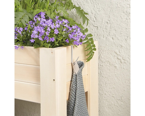 Jardinière en bois avec des plantes à fleurs bleues et une serviette grise sur un crochet