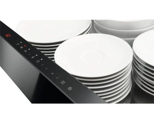 Detailaufnahme eines Kochfelds mit Bedienelementen und gestapelten Tellern