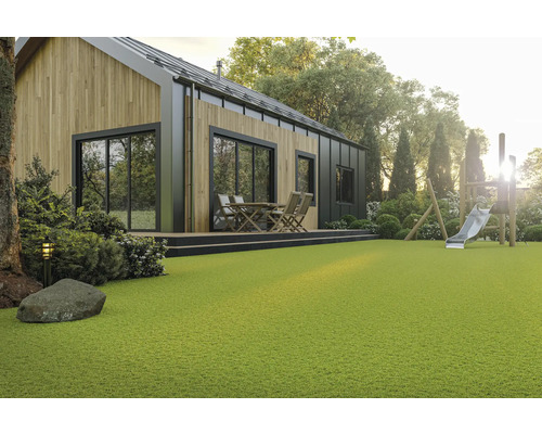 Maison moderne avec façade en bois, terrasse avec coin salon et aire de jeux dans le jardin avec gazon synthétique.