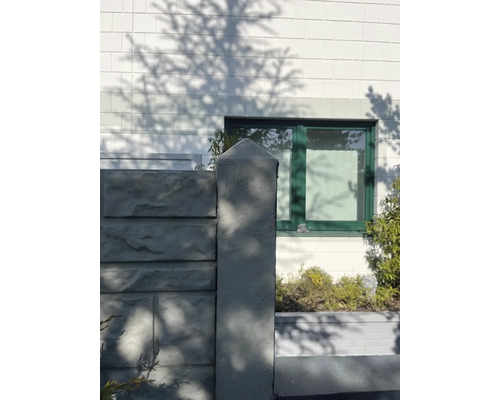 Poteau de clôture en béton devant la façade d''une maison avec fenêtre