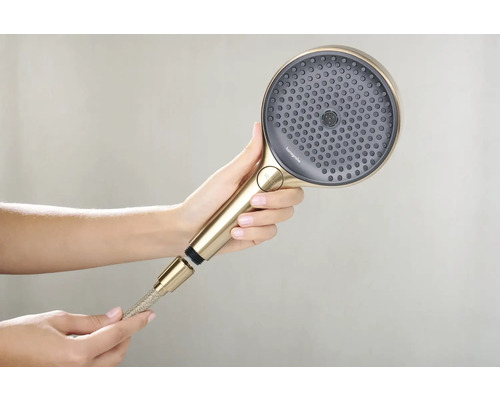 Eine Handbrause mit Brauseschlauch wird von einer Hand gehalten.