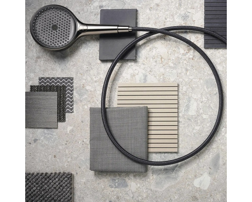 Handbrause mit Duschschlauch, Stoffmustern und Fliesen auf einem Tisch