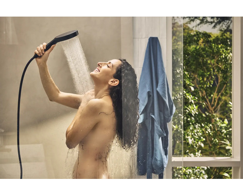 Frau unter der Dusche mit Handbrause und Duschschlauch.